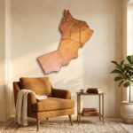 Oman map wall art above a tan armchair in a warm, sunlit living room with a potted plant