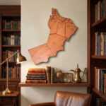 Oman map wall art above a desk in a warm study with bookshelves, globe and brass lamp