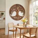 Tree of life wall art above a round dining table in a sunlit kitchen nook with cane chairs