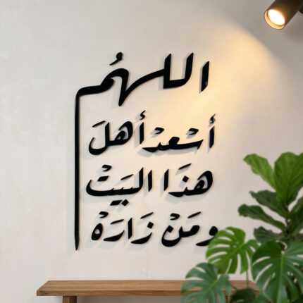 Islamic wall art with black Arabic calligraphy above a wooden shelf and leafy houseplant