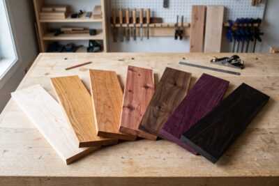 Blue mahoe and other hardwood boards fanned across a workbench in a woodworking shop
