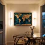 World map wall art above a glass dining table in a warmly lit modern dining room