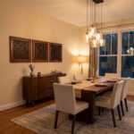 Islamic wall art panels above a sideboard in a warm modern dining room with pendant lights