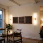 Islamic wall art triptych of geometric Kufic calligraphy above a glass dining table in a warm modern dining room